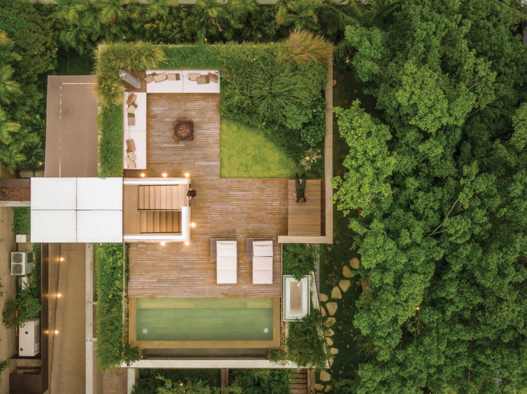 An aerial view of a modernist home surrounded by greenery