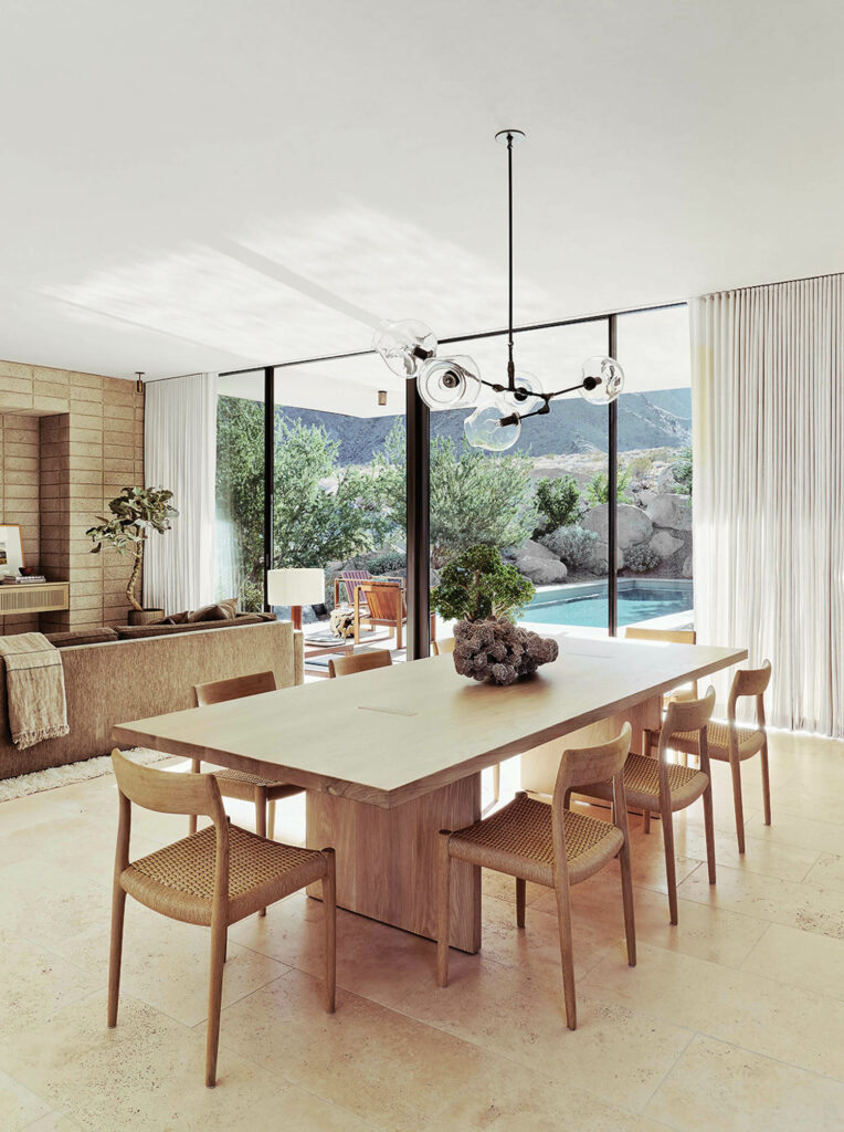 A simple wooden dining table overlooks the pool and surrounding boulders on the property. 