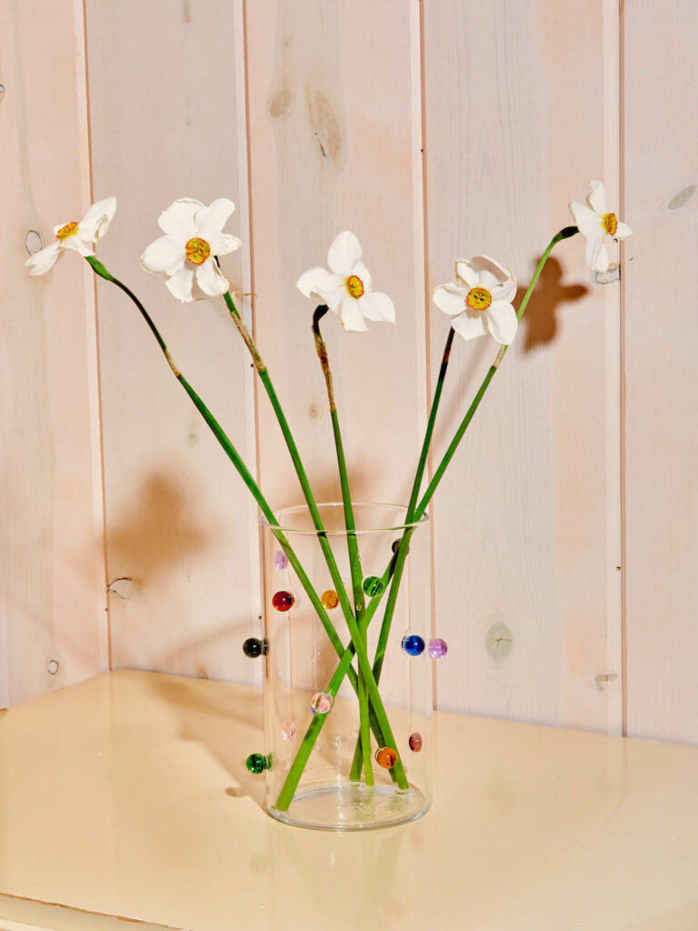 a glass vase with colored dots attached on the outside