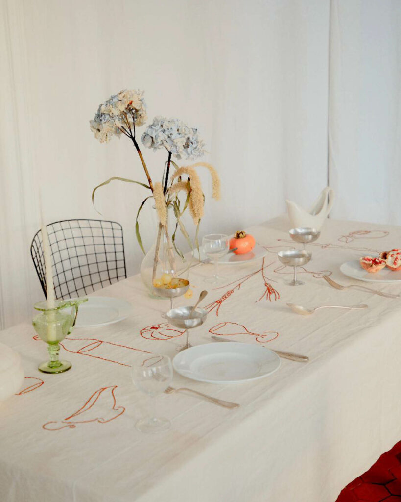 a tablecloth embroidered with red stitching in the shape of various food items and dishes