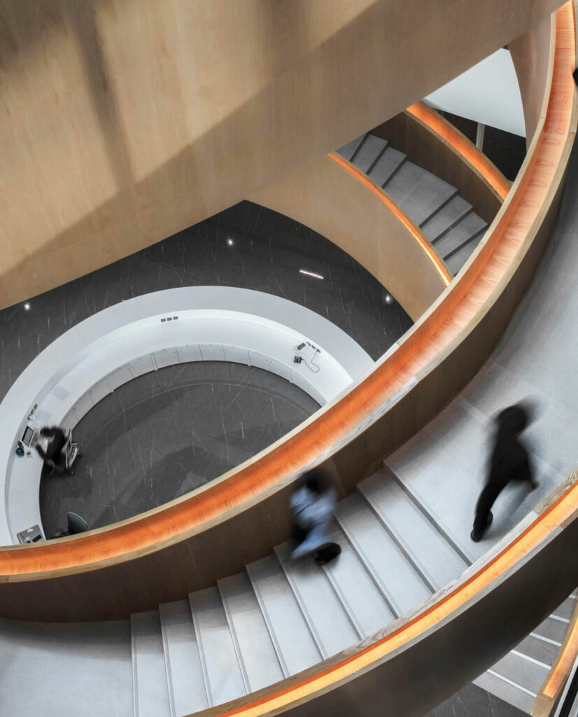 An overhead view of people walking along a winding staircase with wooden edges.