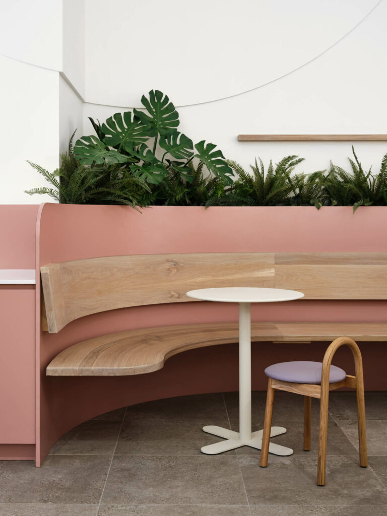 A custom serpentine bench with wood seats and blush colored back rests.