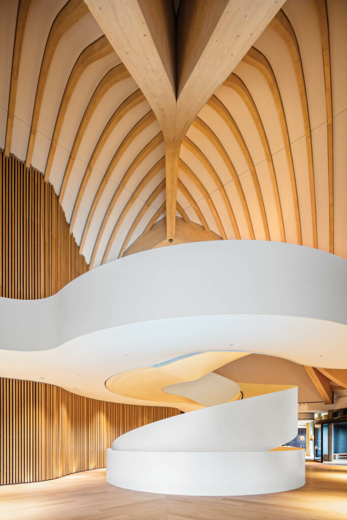 a ceiling braced with spruce beams above a spiral staircase