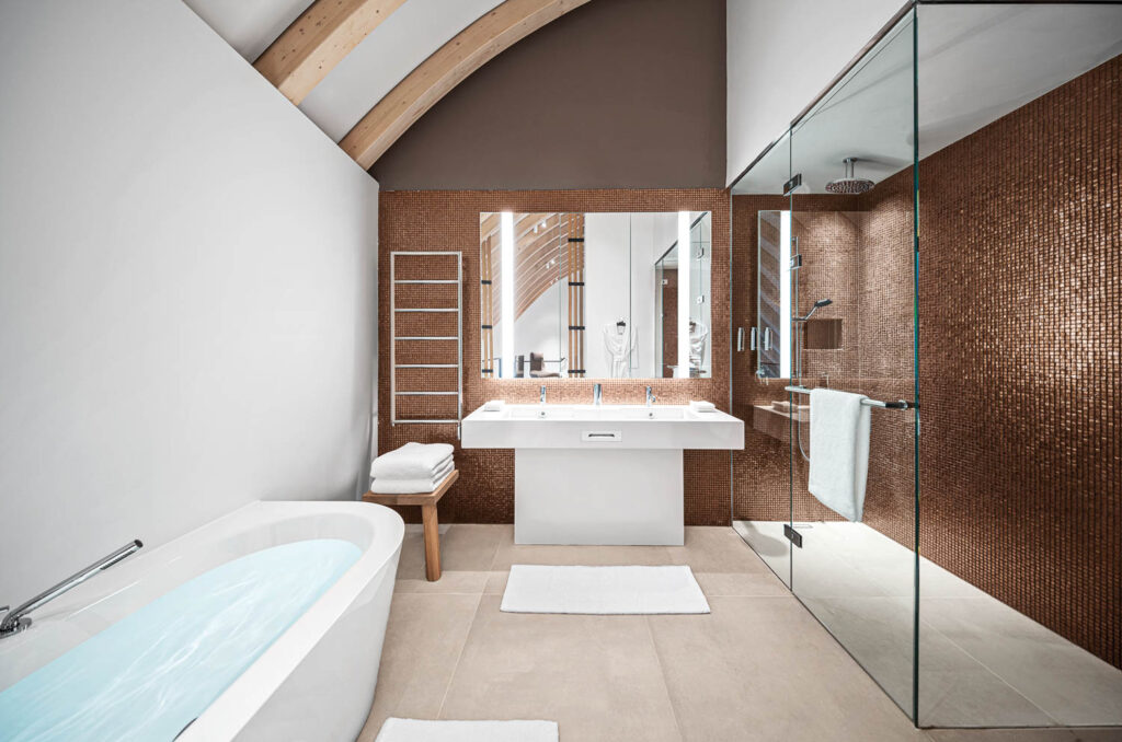 a freestanding tub in front of a large shower in a spalike bathroom