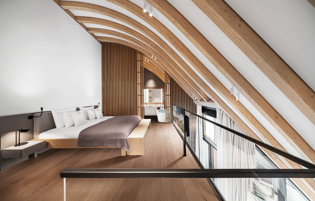 exposed wooden beams curve over a guest bedroom