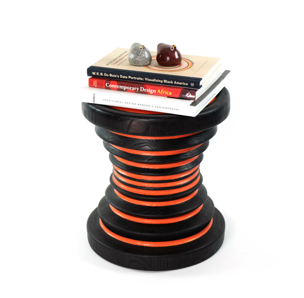 a black and orange side table made of stacked rings with books atop it