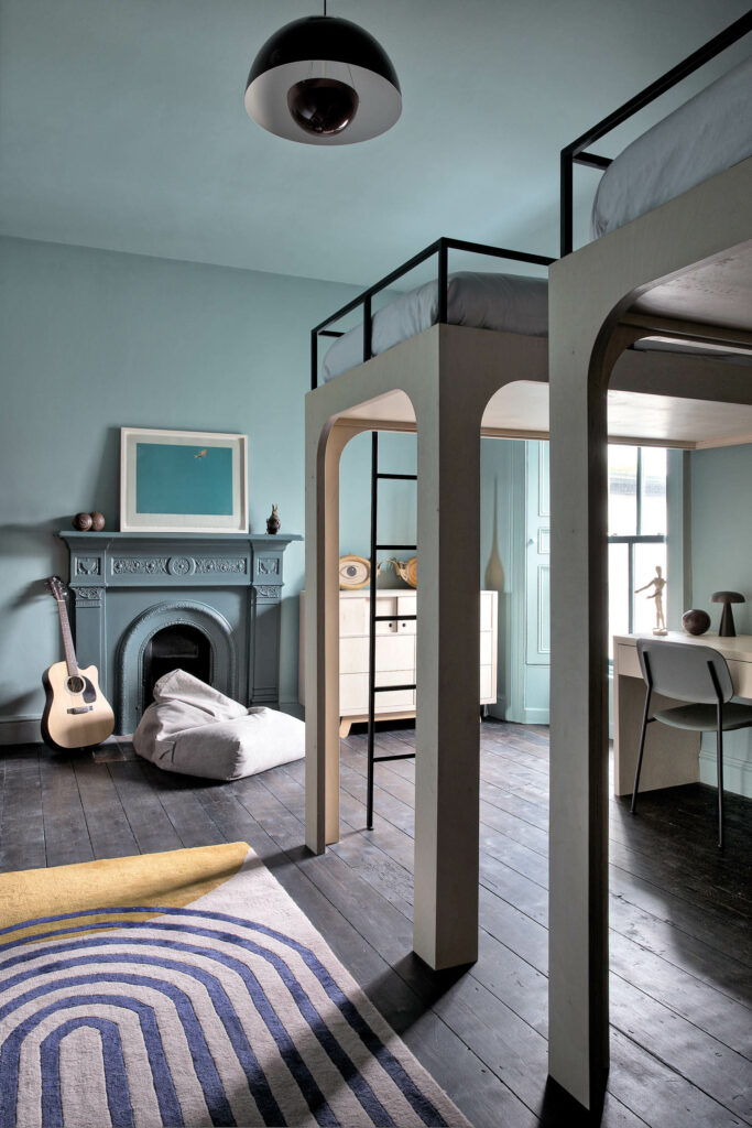 a blue mantled fireplace in a boys bedroom with elevated beds