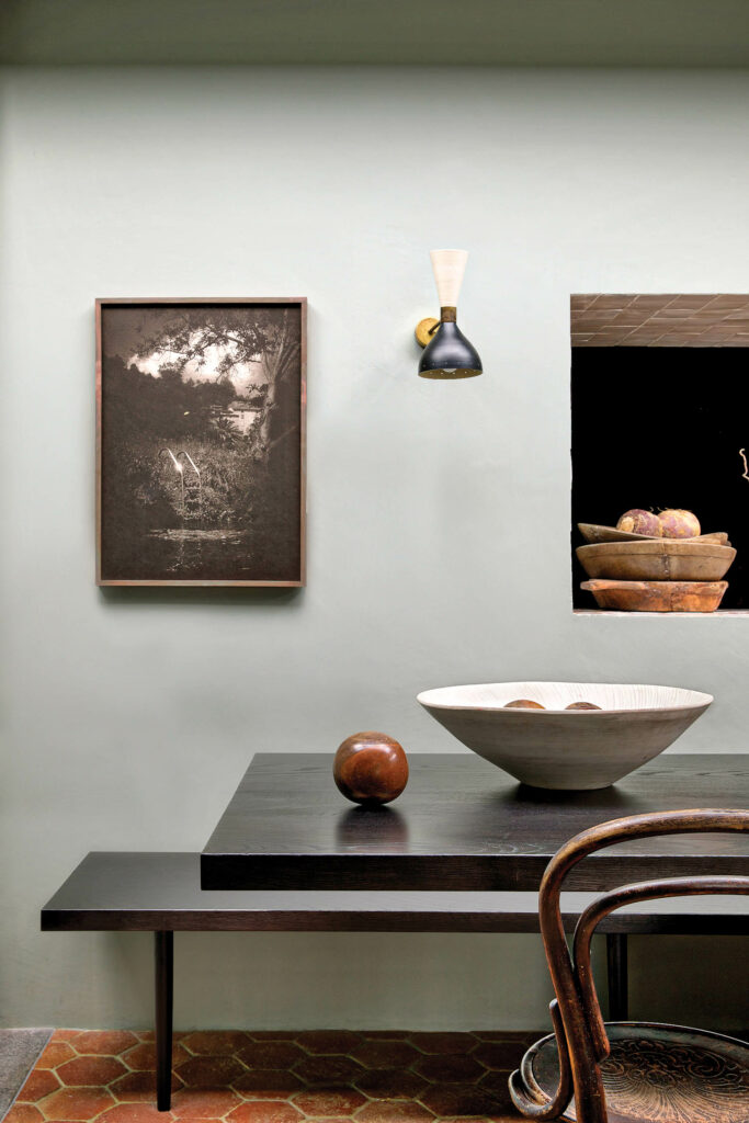 a dining room wall with a Dominic Turner print next to a sconce