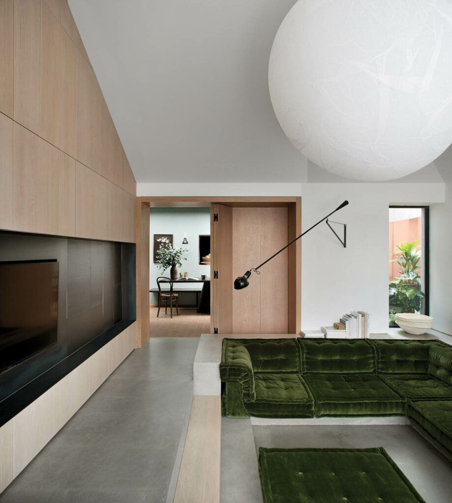 a moon pendant fixture hangs above the green sofa in the conversation pit