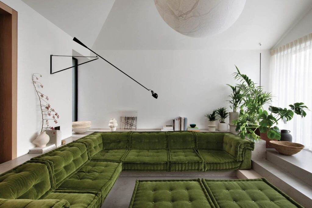 a green velvet sofa in conversation pit of a home