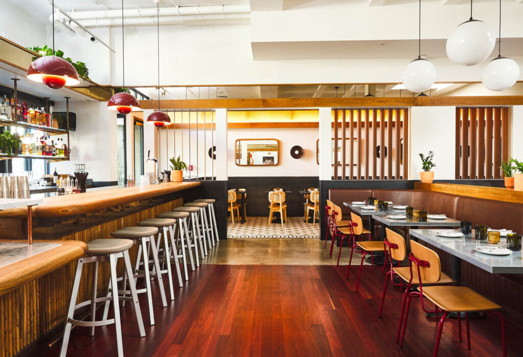 a restaurant with booth seats facing the bar with stools