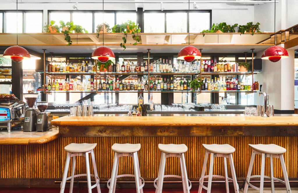 under modern red pendant lights, an oak bar with stained oak tambour across the front