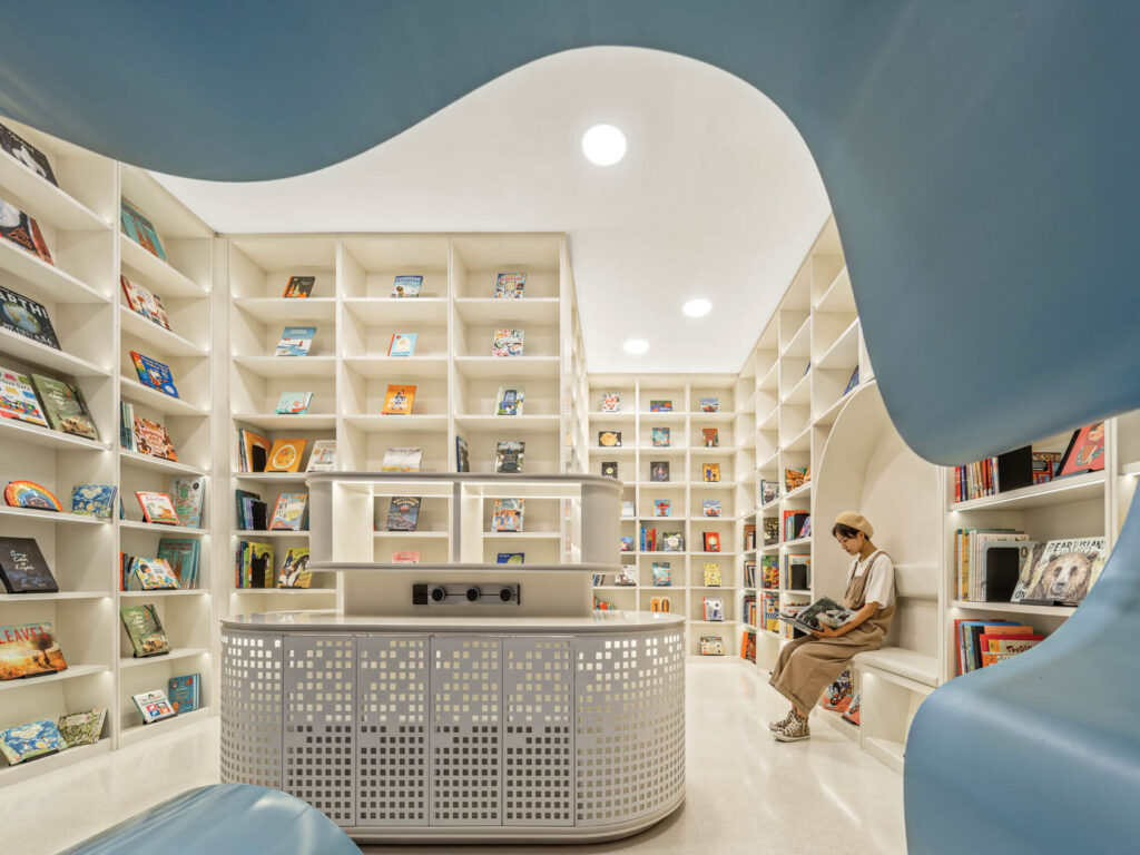 a person reads while sitting upon a bench in a room full of books