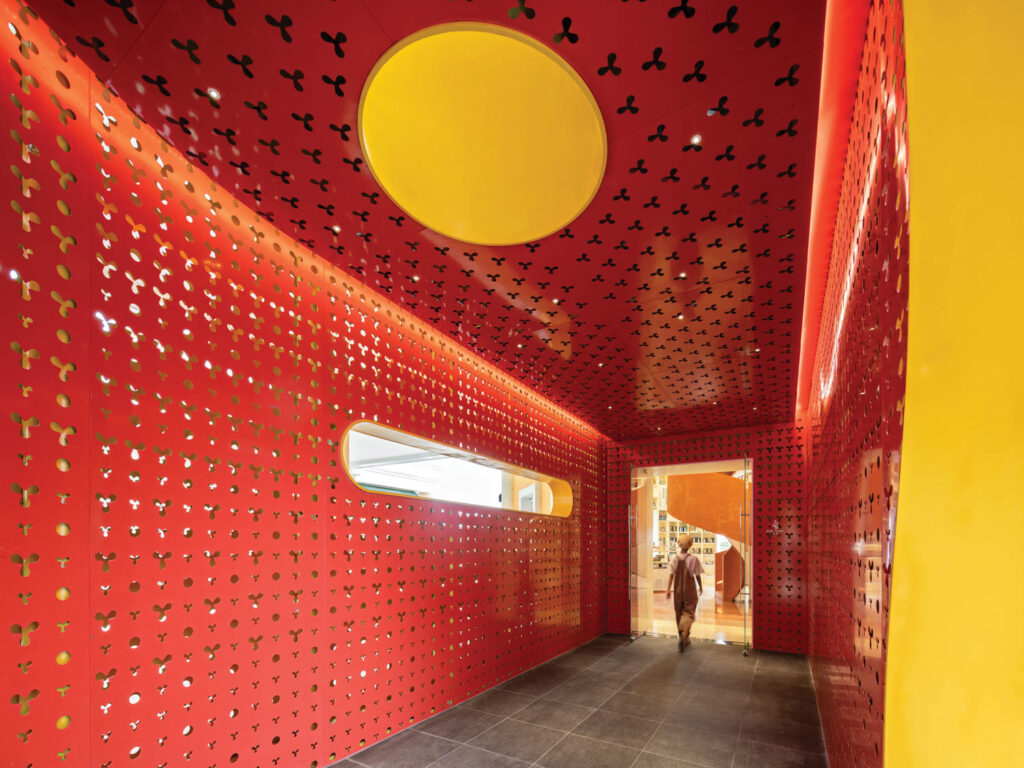 red aluminum panels with curvilinear shapes cut out form a hallway in bookstore