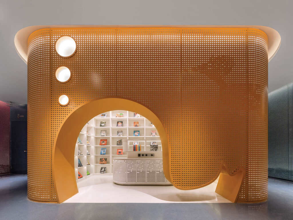 a whale shape cutout on an orange aluminum wall holds the children's area of a library