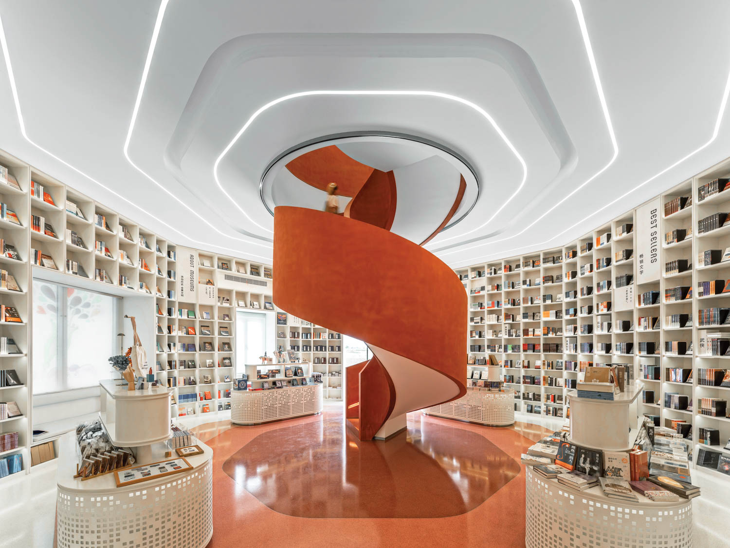 An orange spiral staircase at the center of a bookstore