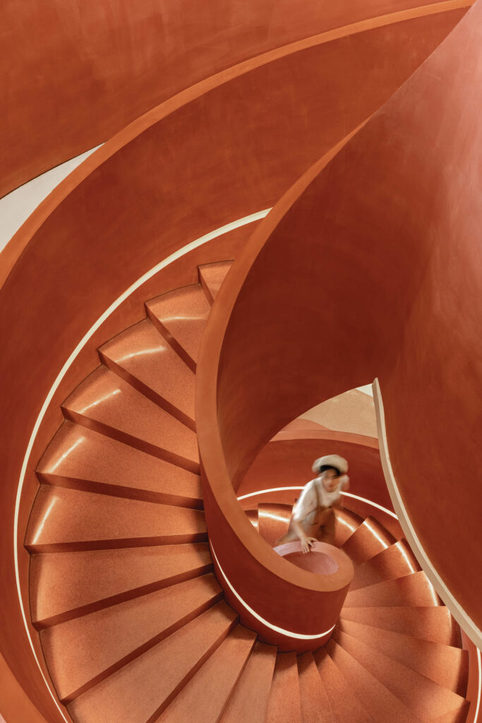 a person walks up an organe sprial staircase with LED strips lighting the way