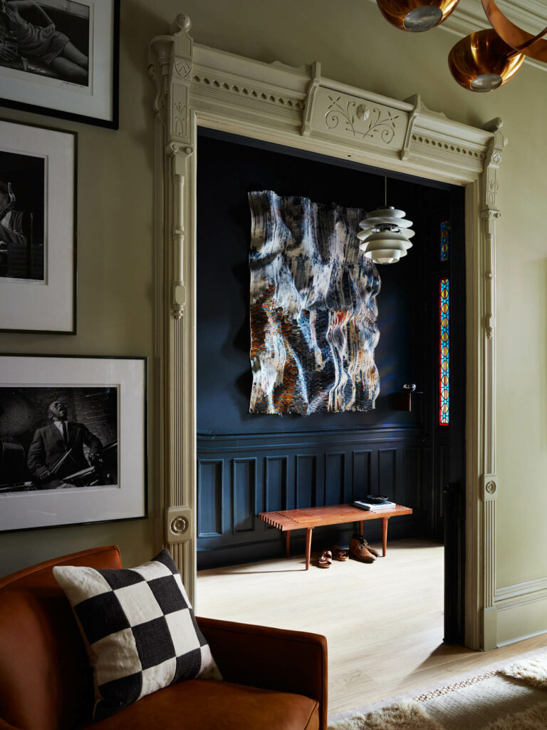 in the entrance to this brooklyn brownstone a blue accent wall boasts a large artwork hanging above a bench