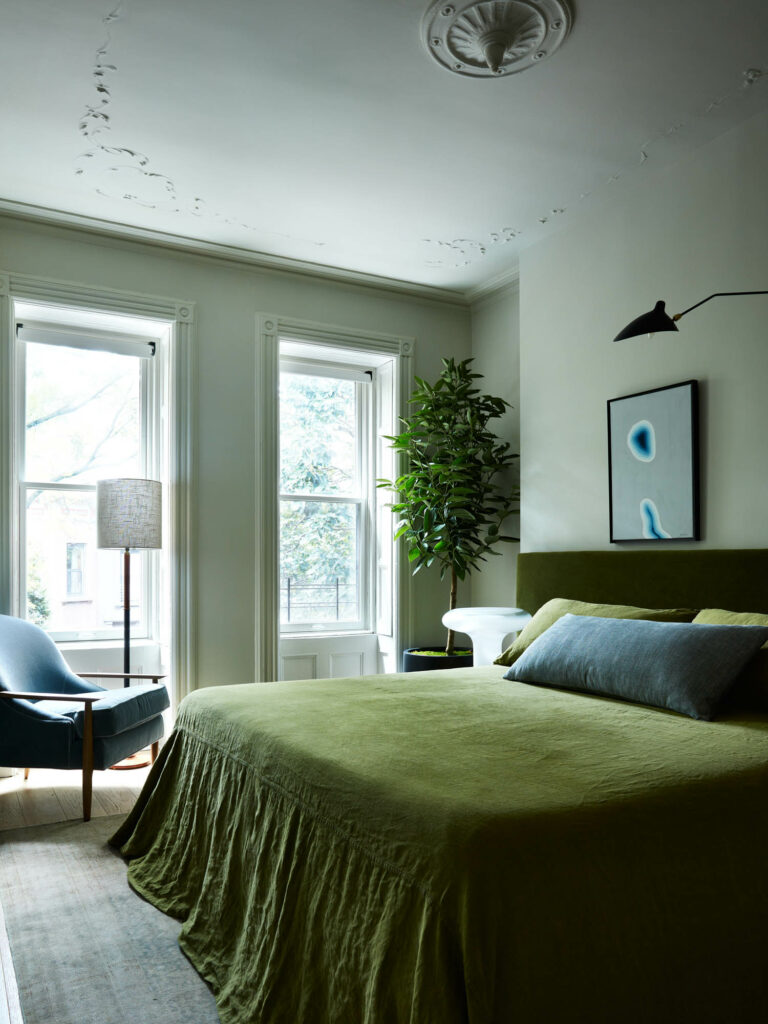 a contemporary Brooklyn home's bedroom with green linens and large windows