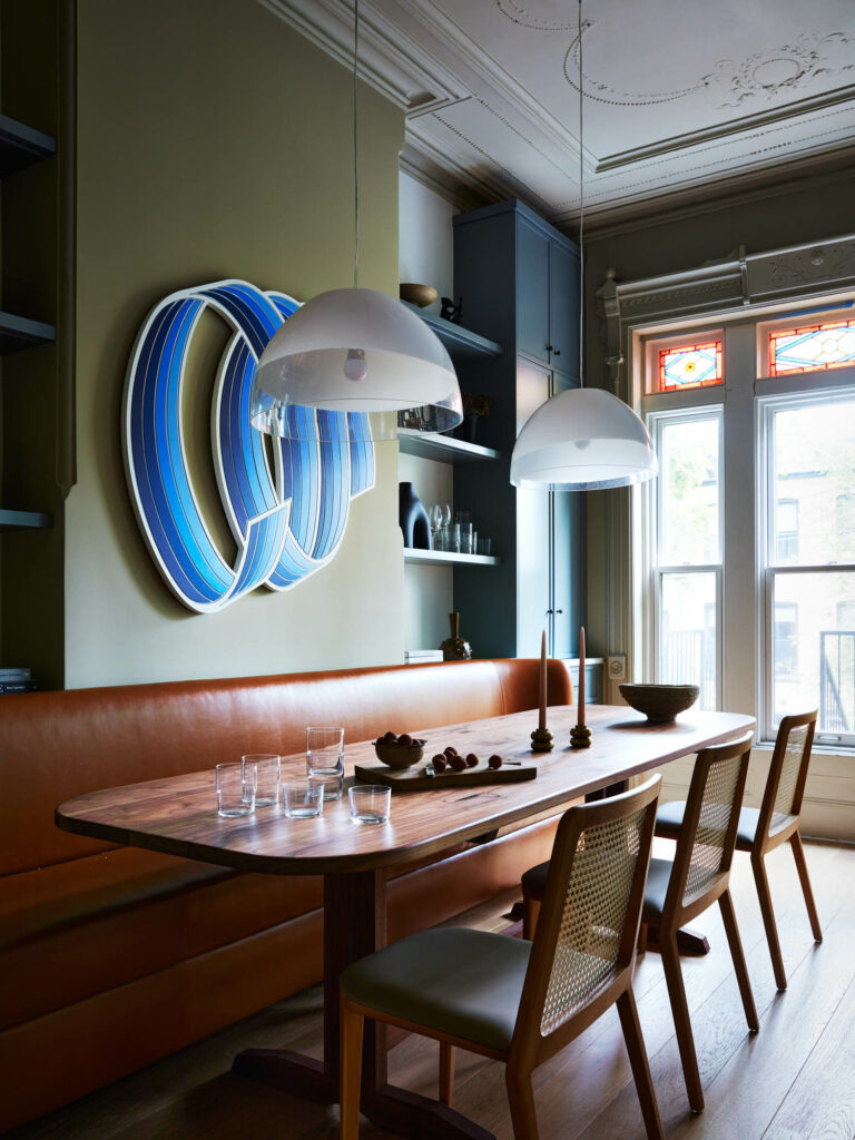 the dining room of a Brooklyn brownstone with leather bench seating and pendant lights