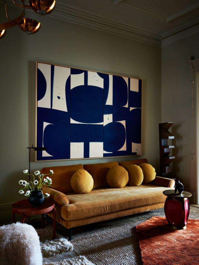 a yellow sofa below a blue and white abstract artwork in a renovated Brooklyn brownstone