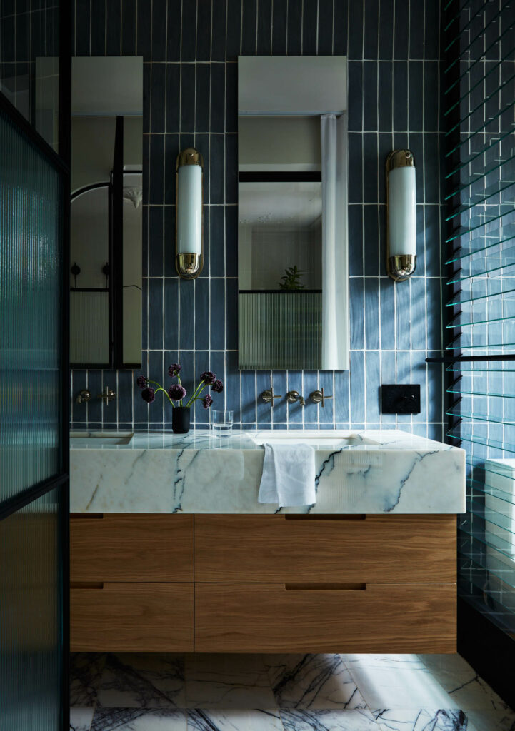 a bathroom with blue vertical tiles and a white marbled countertop