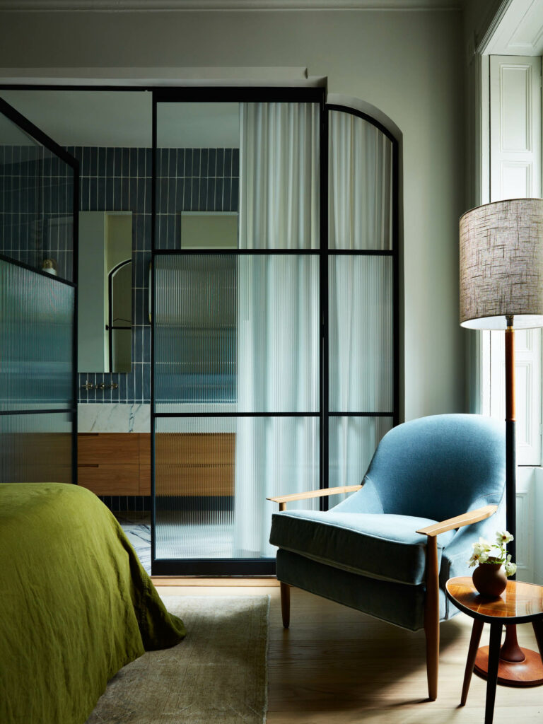 a glass and metal partition separates a bedroom and bathroom in a Brooklyn brownstone