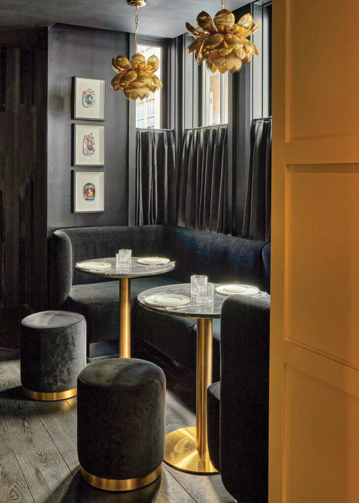 a black-cloaked seating area in a cocktail bar with gold floral pendant fixtures