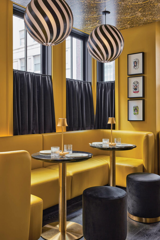 pendant globes hang above a banquette seating and ottomans in a bar