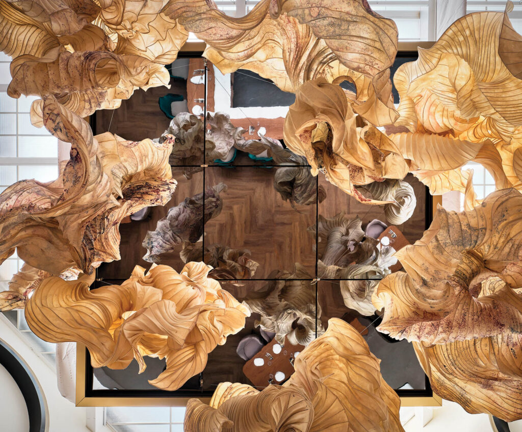 a mirrored ceiling reflects a paper installation and the rest of the dining room in this restaurant