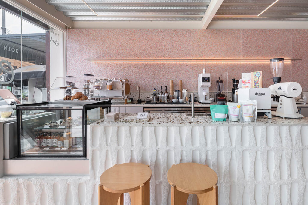 the counter of a Bangkok coffee shop is textured white, and the wall behind is a dotted pink