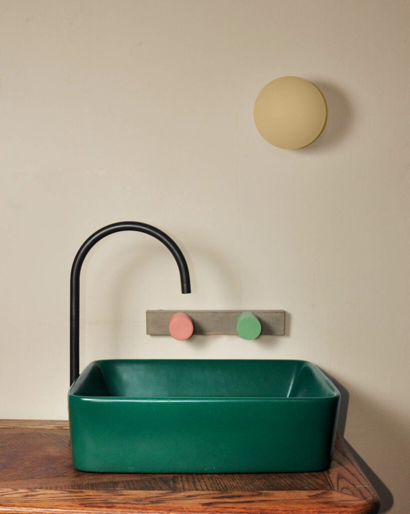 pink and green faucet handles on a concrete backplate