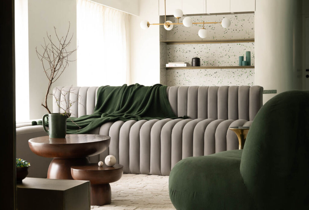 a chandelier hangs above a dining area next to a sofa and armchair in a Mumbai apartment