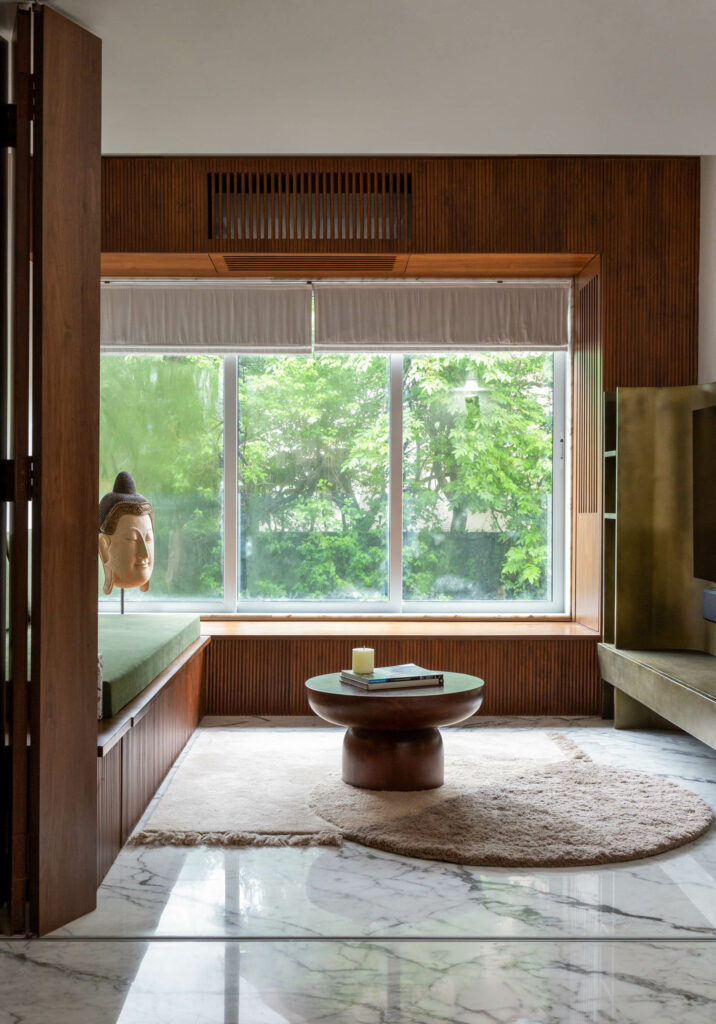 a den area with a coffee table, sofa, brushed brass TV unit, and rug in a Mumbai apartment