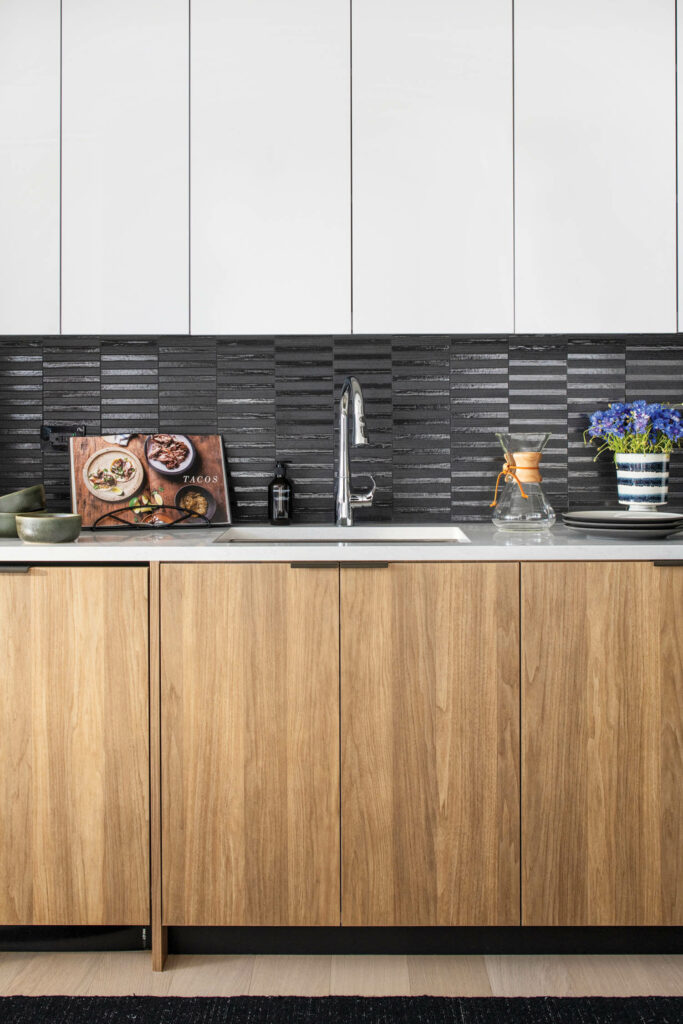 A kitchen sink with wood lower cabinets and white upper ones