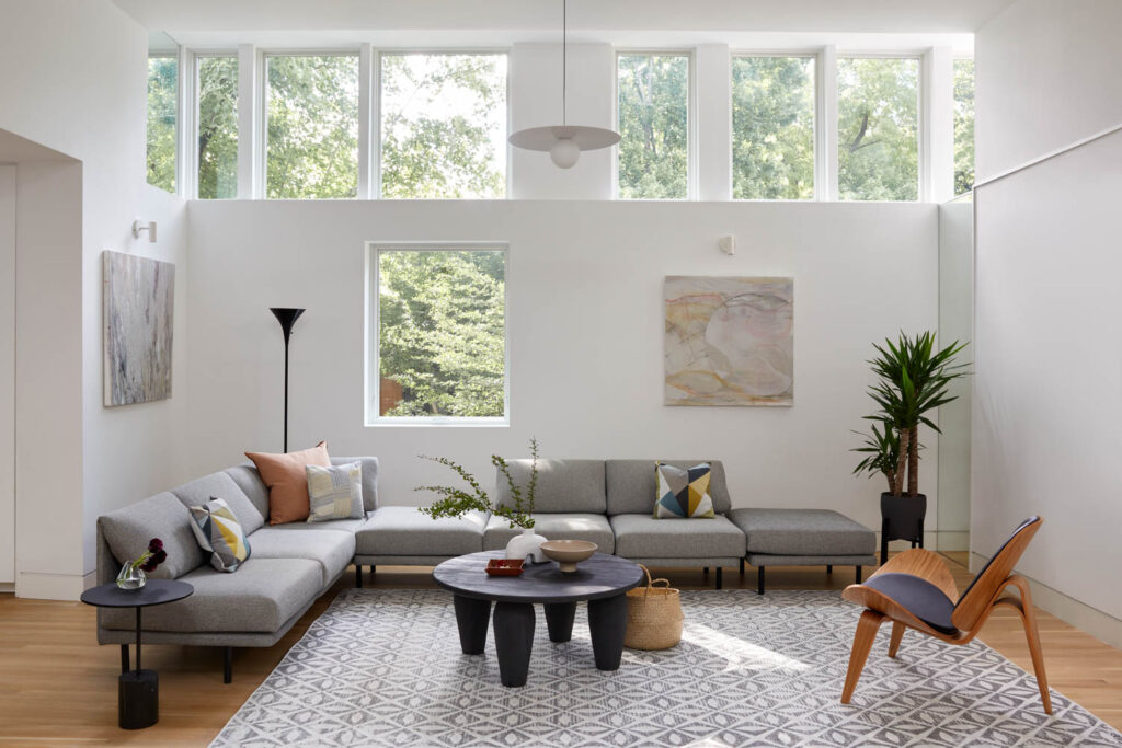 a brightly lit living room with windows lining the top half of the room