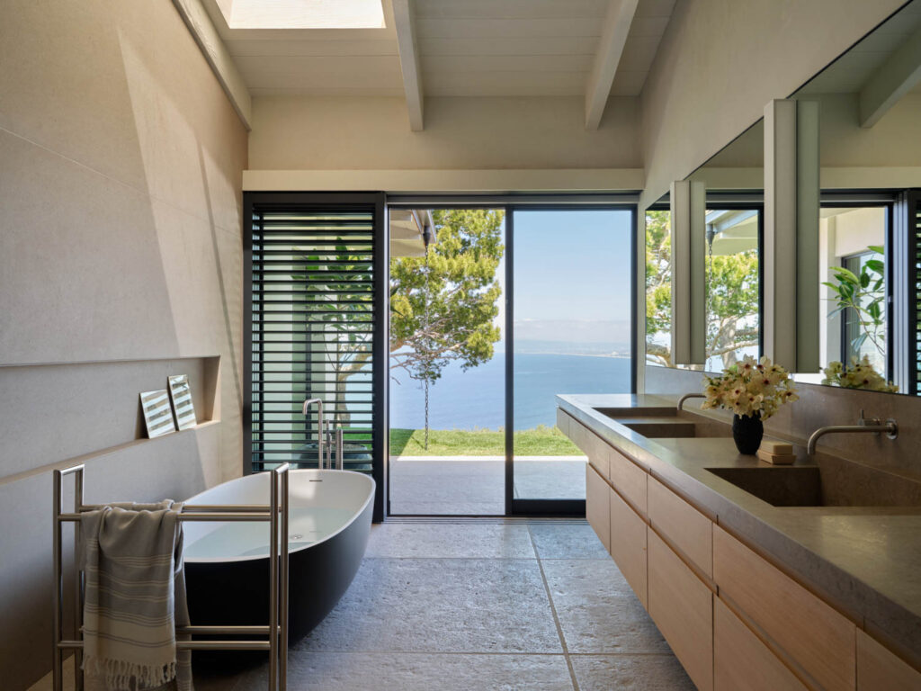 a freestanding tub is across from ash cabinetry in the primary bathroom of a Palos Verdes home