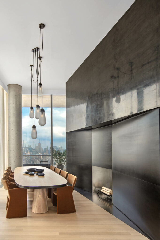 a dining area in front of a fireplace wall clad in Venetian plaster and steel plates