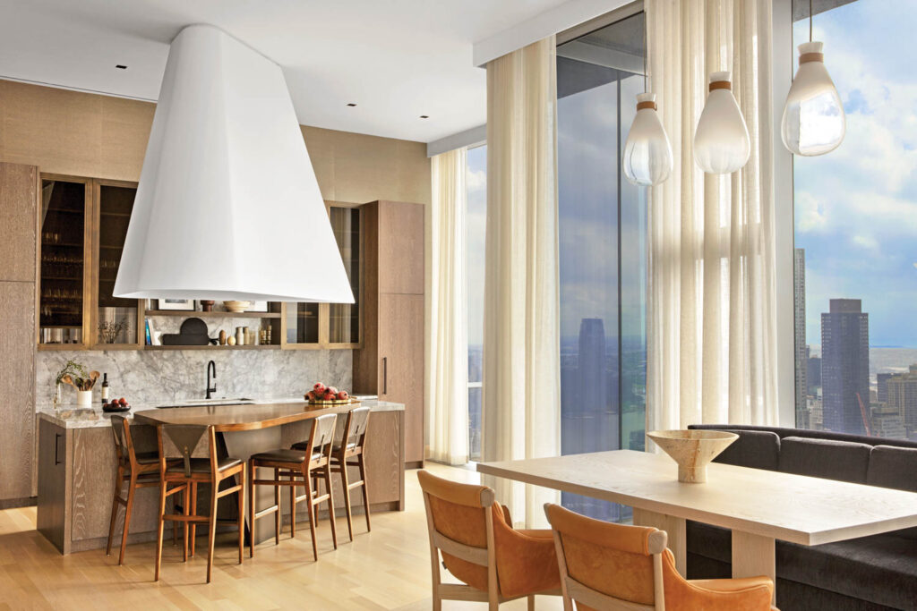 the dining area of an NYC penthouse with a large sculptural stove hood