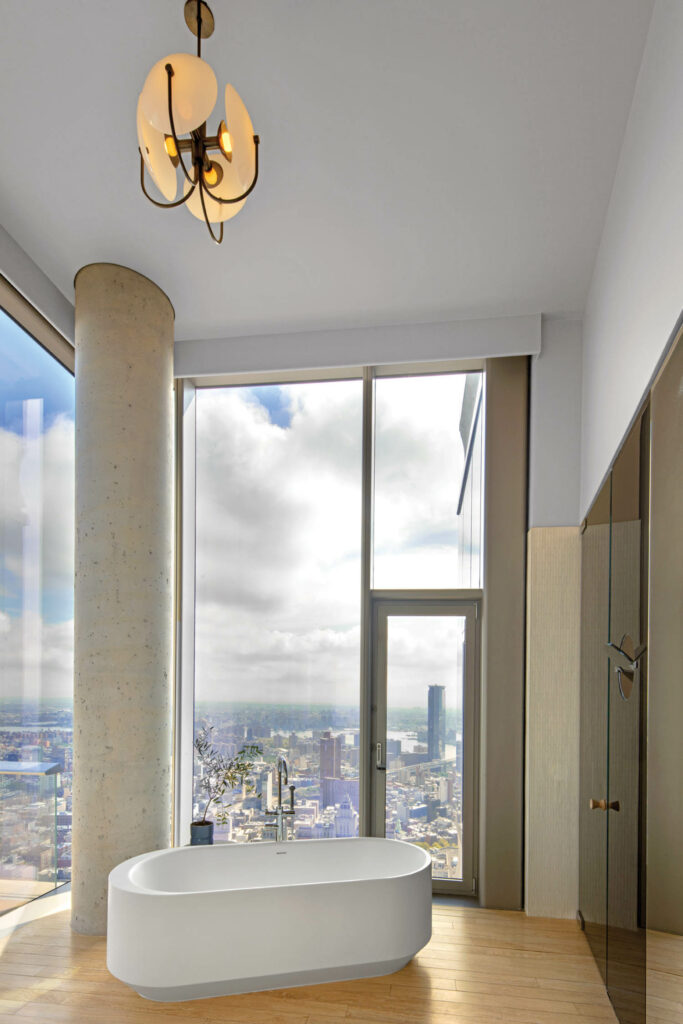 a free standing tub in the bathroom of an NYC penthouse overlooking the city