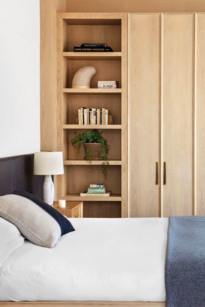 a bed with a custom leather headboard in an apartment by Meyer Davis