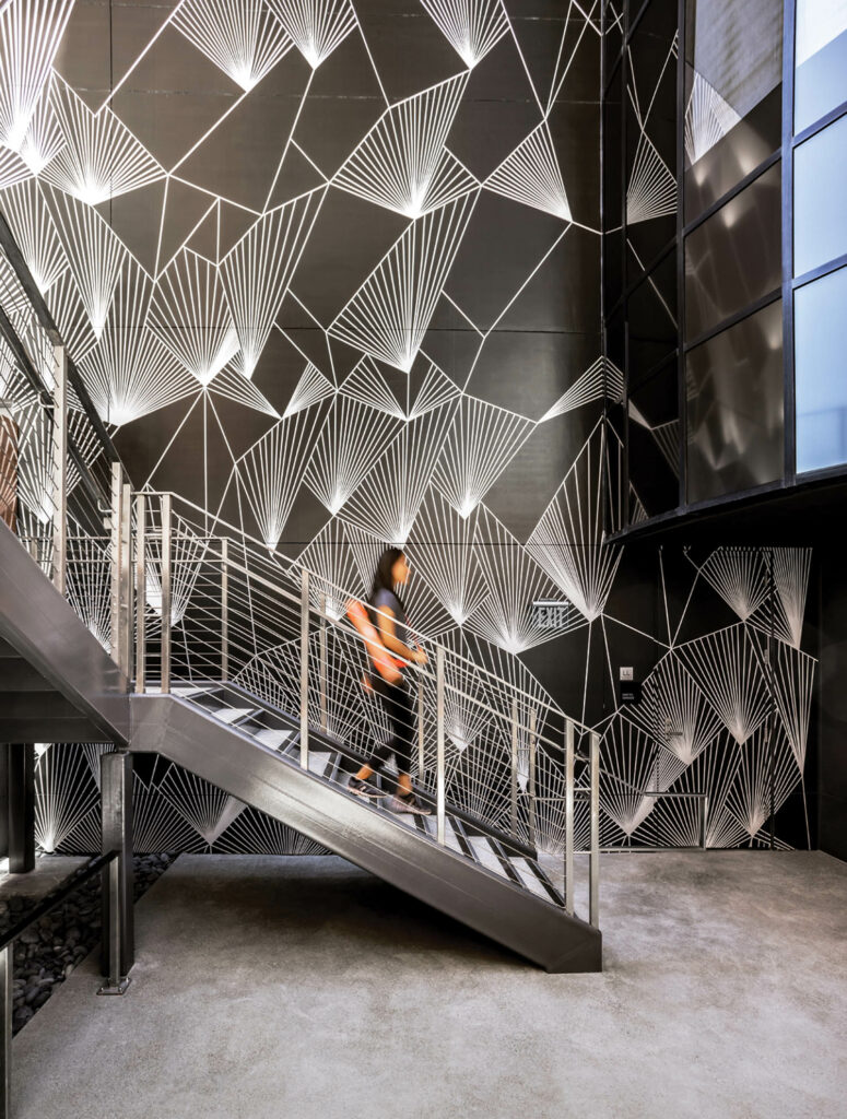 A person walks down a gray stairwell in Santa Clara Towers