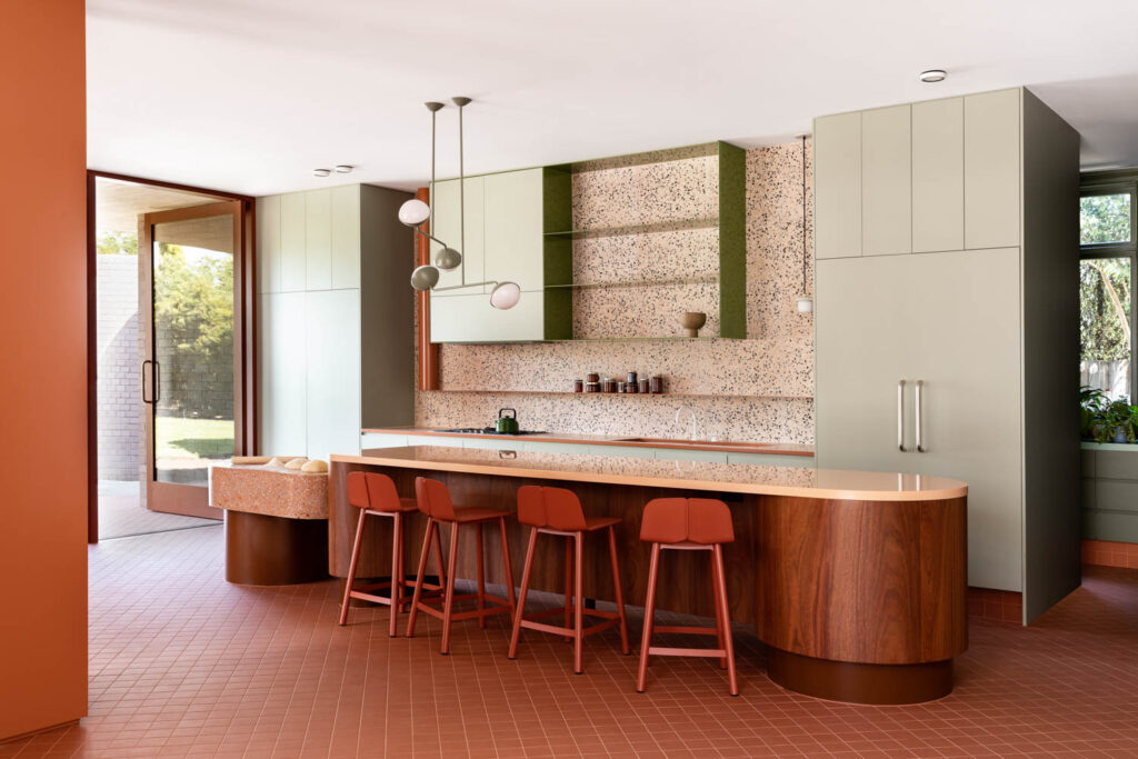 a concrete backsplash and matching countertop lined with stools in the richly colored kitchen