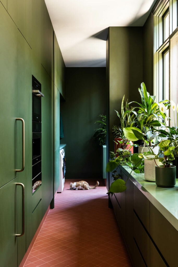 green cabinetry lines the wall of the back-of-house area of the kitchen