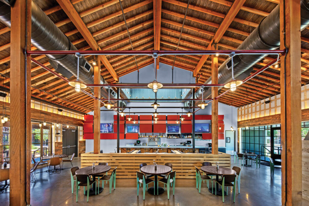 inside Midnight Shift with dining tables and a gabled Douglas fir-beamed ceiling