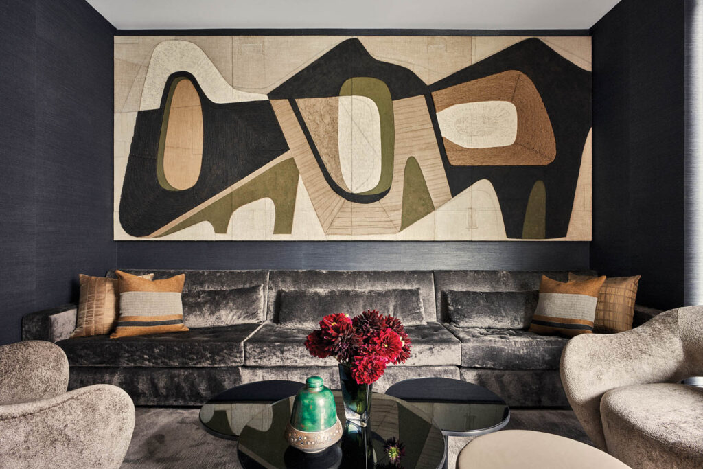 a mixed-media mural hangs above a sofa in the media room of this home