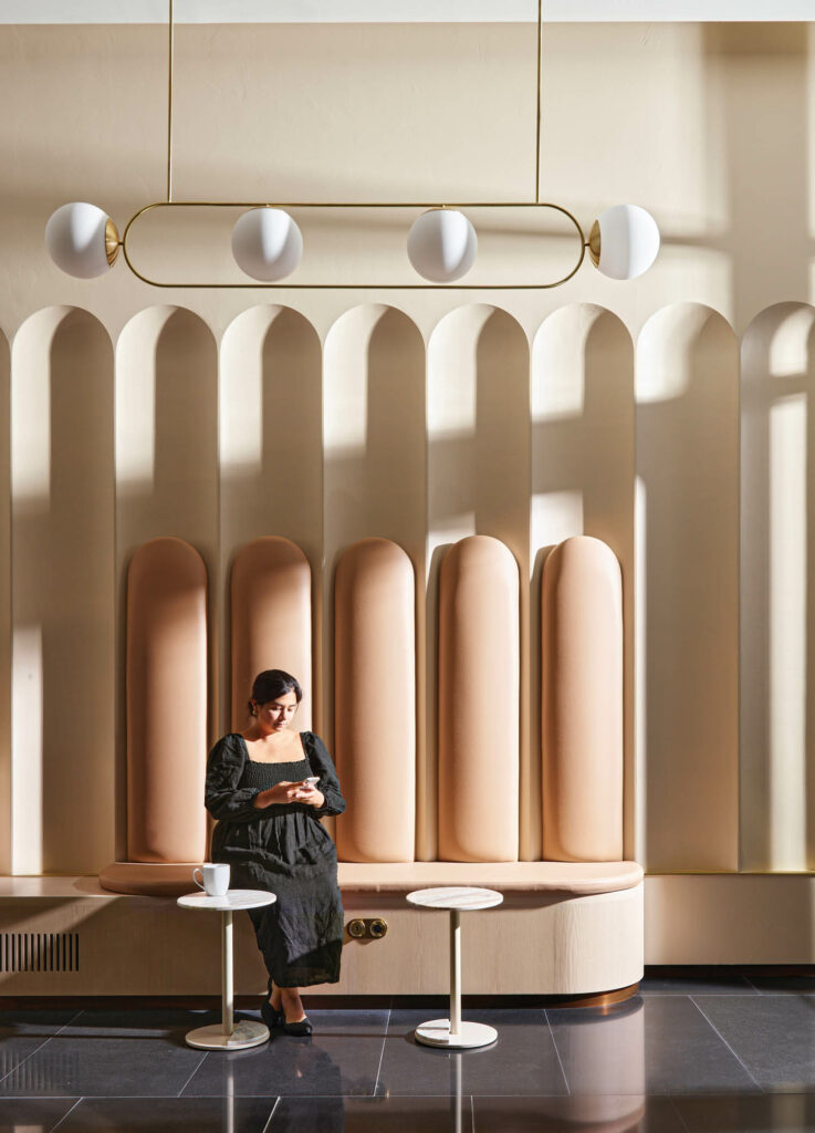 a pendant light hangs above a lobby area, complete with an upholstered bench and coffee tables