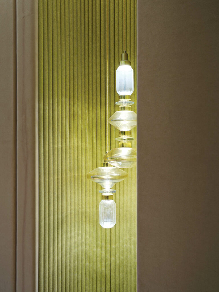 an architectural recess in a model apartment with green upholstery and a custom pendant light