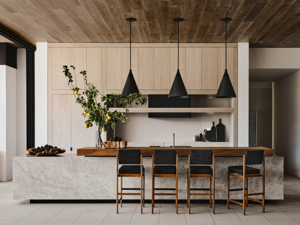 a kitchen with black bar stools and black pendant lights above the island