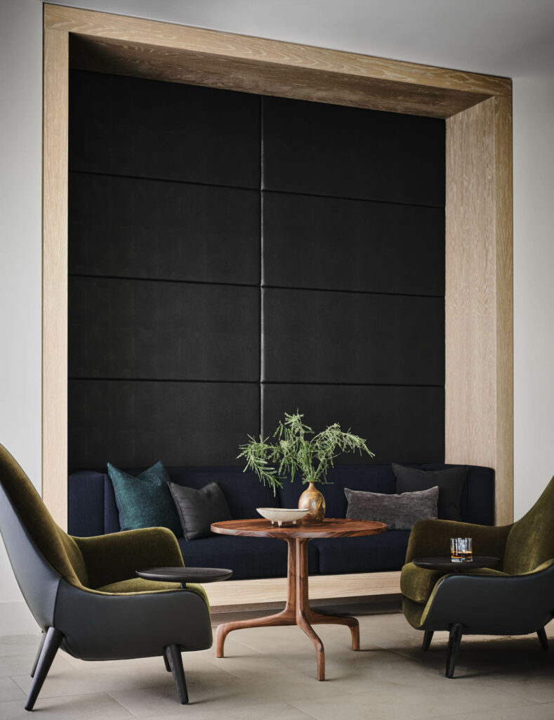 a sitting area in a home with black acoustic paneling behind the sofa